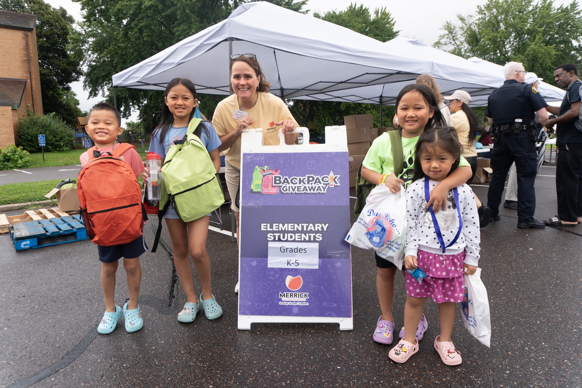 Children and a Merrick staff member at a backpack giveaway
