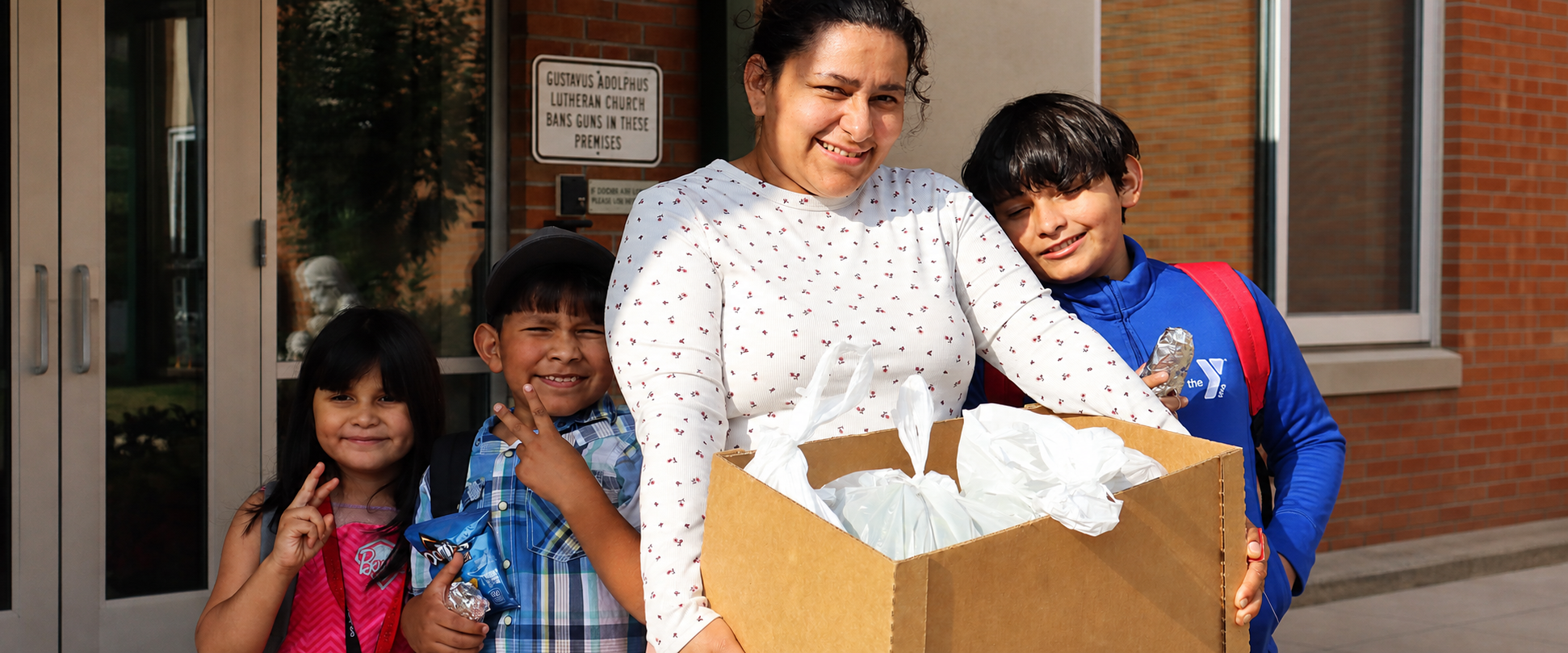 A family carrying a box of food and community resources